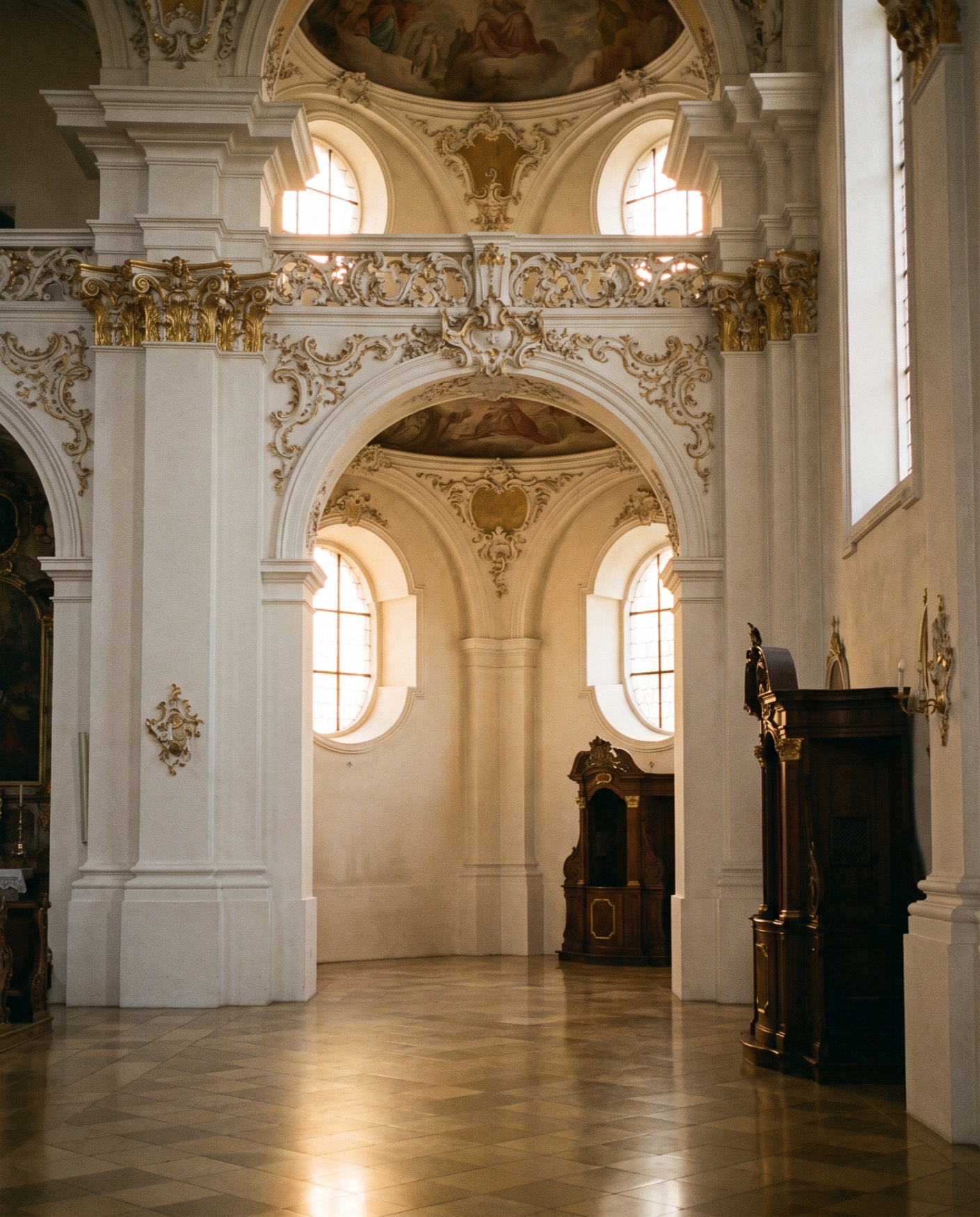 Gilded rocaille, frescoed vaults and a confessional in a high-baroque church